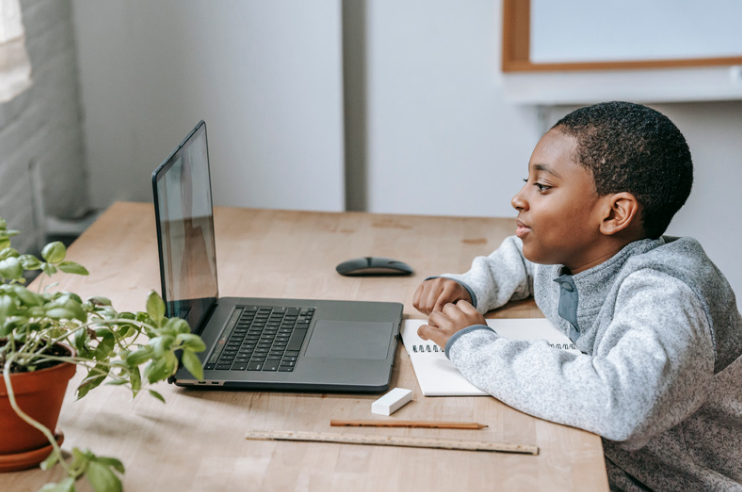 Young student working attentively on a laptop at his desk